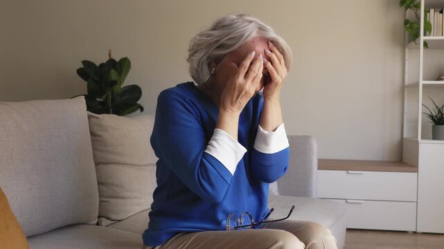 Senior woman suffering from a strong headache at home