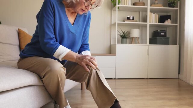 Elderly woman suffering from knee pain at home