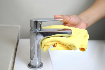 The staff cleans the faucets in the bathroom.
