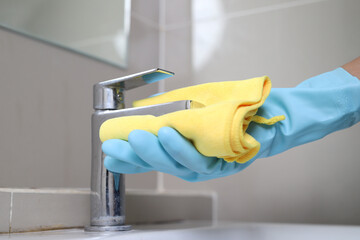 The staff cleans the faucets in the bathroom.