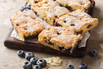 Blueberry Breakfast Cake is bursting with fresh berries and topped with crunchy slivered almonds closeup on the wooden board on the table. Horizontal