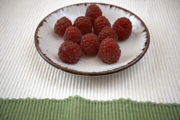 Fresh raspberries served on a small plate. Close up view with shallow depth of field.