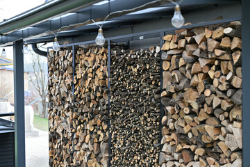 Wood for the winter stored in iron decorative racks against the wall of the house