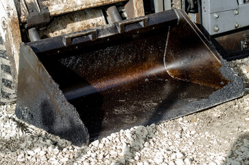 Construction workers in high-visibility gear are applyin gfresh hot asphalt to roadway surface