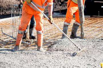 Concrete pouring process at a construction site with builders and concrete pump