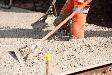 Close-up of Builder uses spazzle to evenly level freshly mixed concrete on construction site ensuring smooth and durable surface