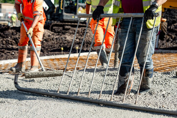 Concrete pouring process at a construction site with builders and concrete pump