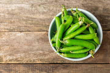Fresh green pea pods with green peas on a wooden background. Sweet green peas. Green pea beans vegetables. Vegan. healthy vegetable. Copy space