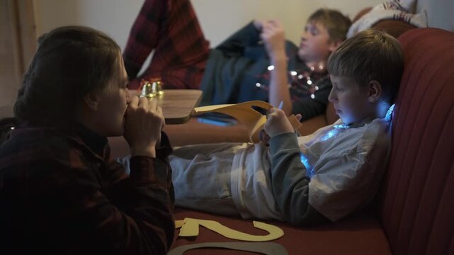Relaxed family celebrates New Year's Eve, mother talking warmly with son on decorated cozy sofa