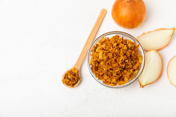Crispy fried onions in a bowl on a wooden table. Roasted Onions. Seasoning for dishes. Spices. Salad dressing. Space for text. Copy space