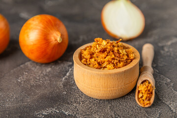 Crispy fried onions in a bowl on a wooden table. Roasted Onions. Seasoning for dishes. Spices. Salad dressing. Space for text. Copy space