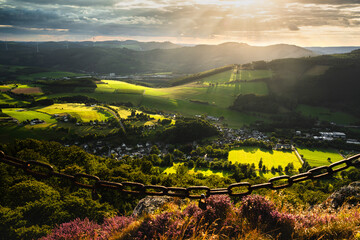 The Sauerland landscape seen from Bruchhauser Steine ​​in Olsberg, Germany, at sunset. Beautifully lit fields and mountains with wind turbines in the background.
