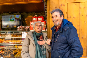 Fototapeta premium Happy senior couple enjoying christmas market in winter city