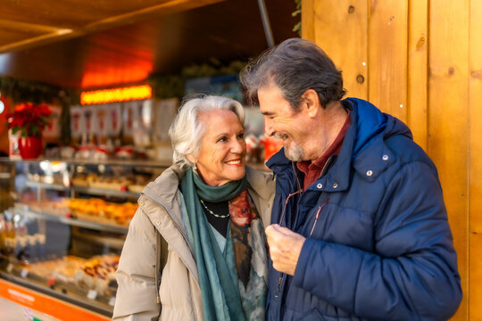 Happy senior couple smiling at christmas market in winter