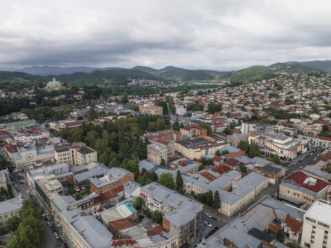 Aerial view of the city's mix of terracotta rooftops and verdant trees, overlooked by the Bagrati Cathedral perched on Ukimerioni Hill, Kutaisi, Imereti, Georgia.