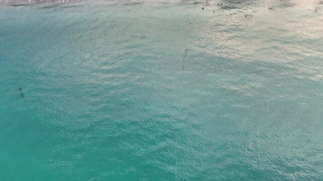 Aerial View of Tropical Beach with Clear Turquoise Water, Swimmers, and Traditional Boats
