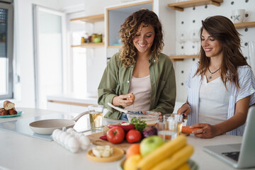 Young Women Cooking Together in a Bright Modern Kitchen with Fresh Ingredients and Happy Smiles