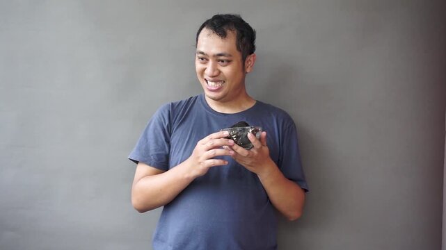 Footage of asian man show awfull eat chocolate cake on isolated grey background