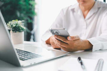 Close-up businesswoman using smart mobile phone at office table, female student is home studying online e-learning, searching for information on internet, engaging with social networks.