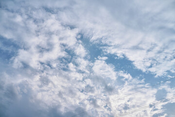 Obraz premium Vast Sky Filled with Wispy Clouds and Distant Birds Flying in Formation Under the Bright Sunlight