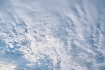 A Vast Expanse of Textured Clouds with a Flock of Birds Flying in Formation Against a Bright Blue Sky
