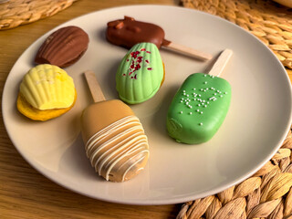 Assorted desserts on a plate, colorful cakes and popsicles. Modern food styling. Concept of variety, sweets, aesthetics of food.