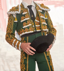 Young matador in ornate green traje de luces holding a montera during a Practical lesson at Corrida...
