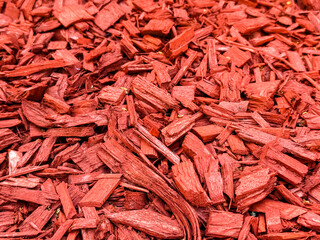 Red wood chips arranged as mulch creating a rough surface texture for landscaping and decoration. Organic recycling, natural material and environmental resource for gardening and ecological design.