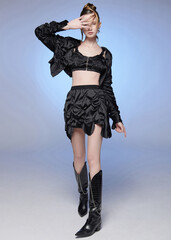 Young woman in stylish black outfit posing with a hand on her forehead.