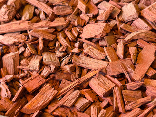Red wood chips arranged as mulch creating a rough surface texture for landscaping and decoration. Organic recycling, natural material and environmental resource for gardening and ecological design.