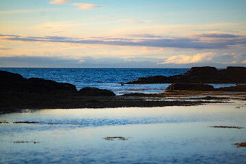 Fototapeta premium Rocky Sea Shore with Calm Water at Sunset