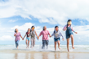 Happy Asian multi-generation women family travel nature ocean on summer beach holiday vacation. Grandmother and granddaughter enjoy outdoor active lifestyle walking and playing together in the sea.