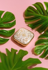A luxurious, gold-toned compact mirror rests prominently on a soft pink surface, surrounded by vibrant green monstera leaves. The leaves, with their characteristic deep green color and glossy texture