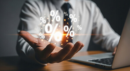 Naklejka premium A man in a white shirt holding percentage symbols above his hand with a laptop on the desk near him