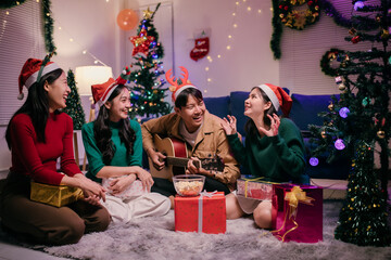 Group of friends singing christmas carols while playing acoustic guitar at home