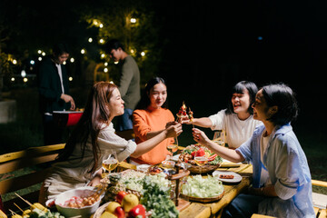 Friends enjoying barbecue party at night with skewers and wine glasses