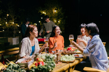 Friends enjoying barbecue party, drinking wine and eating together at night