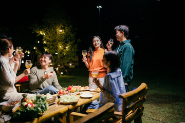 Friends enjoying garden party with food and drinks at night