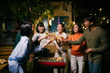 Friends toasting with wine glasses at barbecue backyard party
