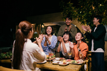 Friends clapping and laughing during a backyard party at night