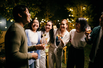 Asian friends enjoying drinks at a night party in the garden
