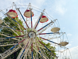 Large ferris wheel attraction in amusement park under blue sky. Leisure, entertainment, and tourism expressed through recreation, adventure, and urban culture.