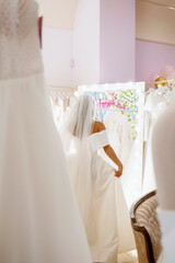 Bride in a magnificent wedding dress and veil standing in front of a mirror