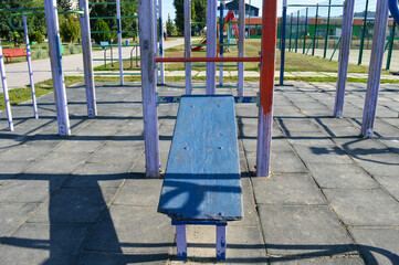 outdoor workout area with gymnastic bars, pull-up structure and exercise bench for strength training and fitness activities in public park