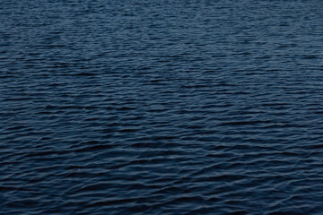 Abstract close-up of dark blue water surface with natural ripples and wave patterns