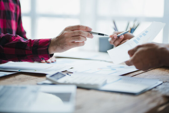 Business people analyzing financial charts and graphs using calculator and pen