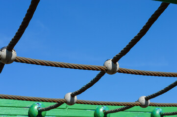 colorful playground climbing net structure with ropes and wooden frame colorful safe equipment for kids, promoting motor skills, active recreation, family leisure, urban infrastructure and outdoor fun
