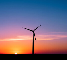 Fototapeta premium A single wind turbine silhouette against a gradient sunset sky