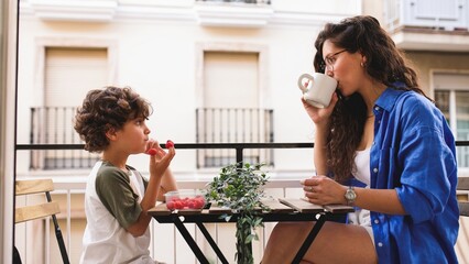 Mother and son enjoying breakfast on balcony: sharing a peaceful moment