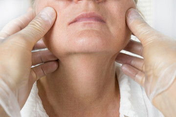 Doctor examine older woman face wearing gloves